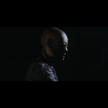 The image depicts the Archon, one of the characters from the film: a figure with a monstrous face shrouded in darkness.